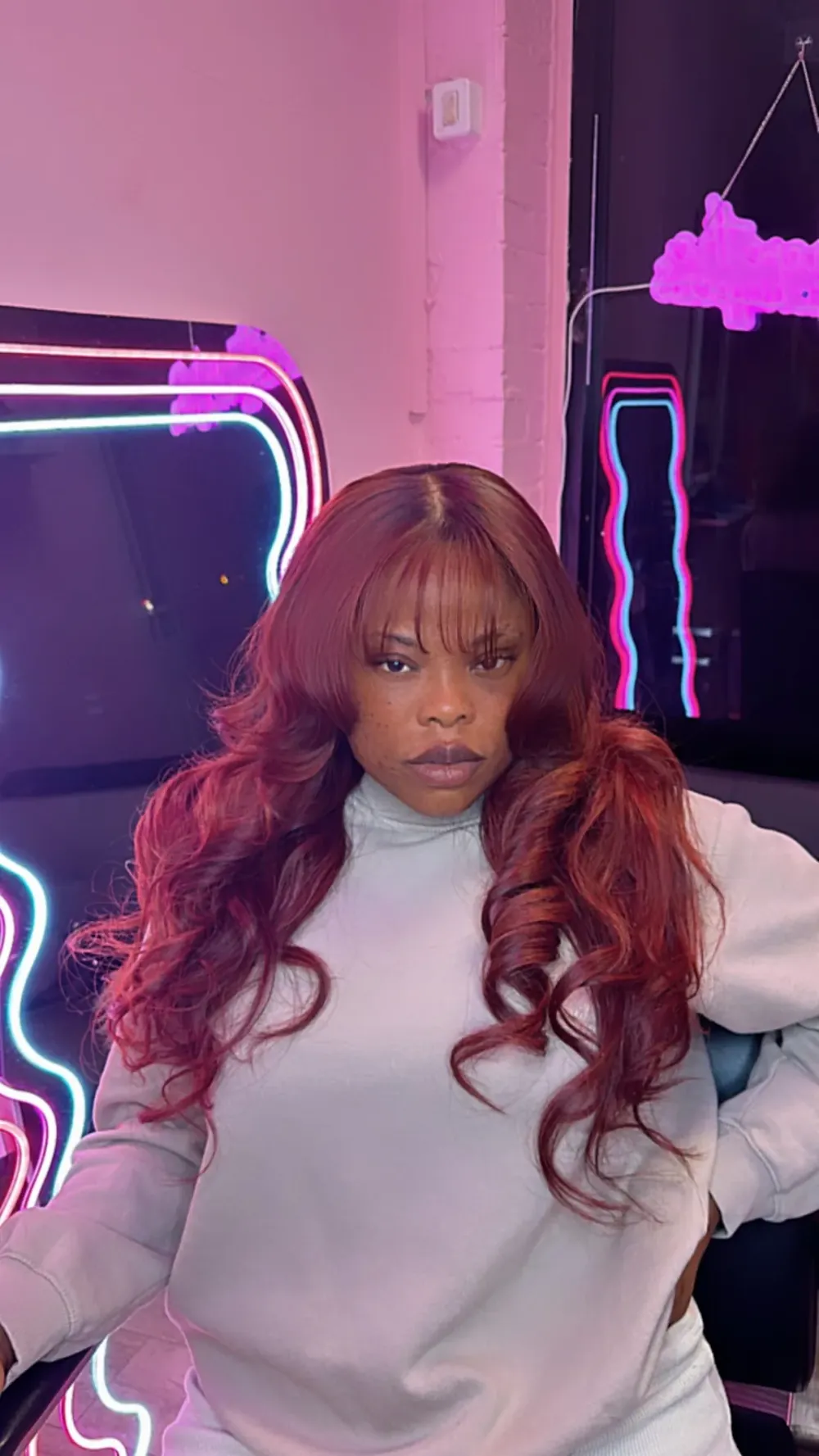 Copper wig styled in front of the pink neon mirrors at SYM’S